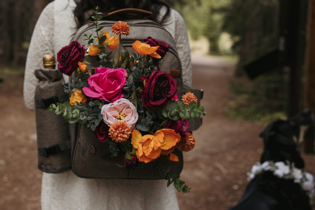 Flowers sit in a hiking backpack for a couples elopement.