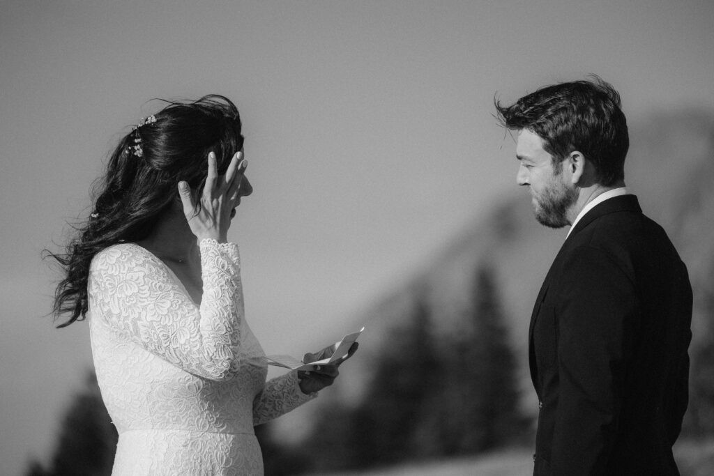 A black and white image of a bride getting emotional while reading her wedding vows.