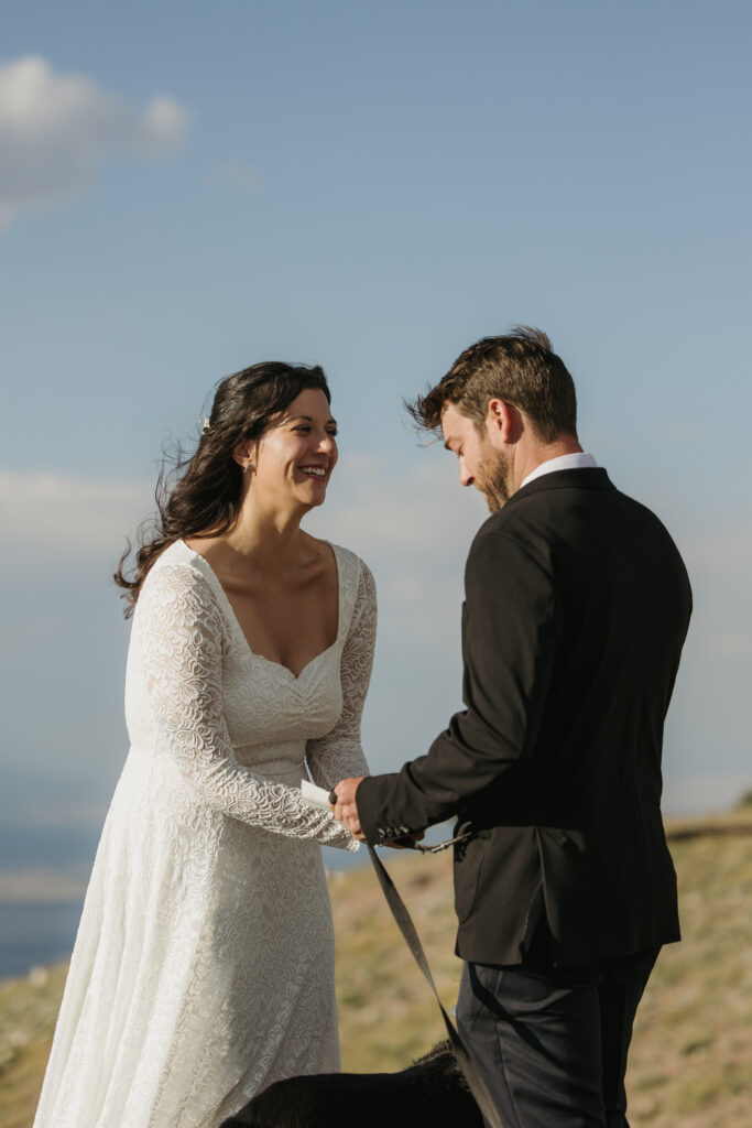 A bride laughs as her partner reads his wedding vows to her.