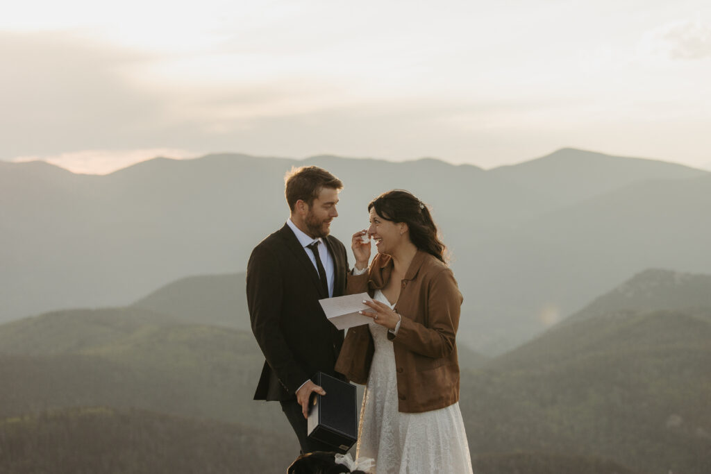A couple cries with the mountain horizon in the background while reading letters during their elopement.